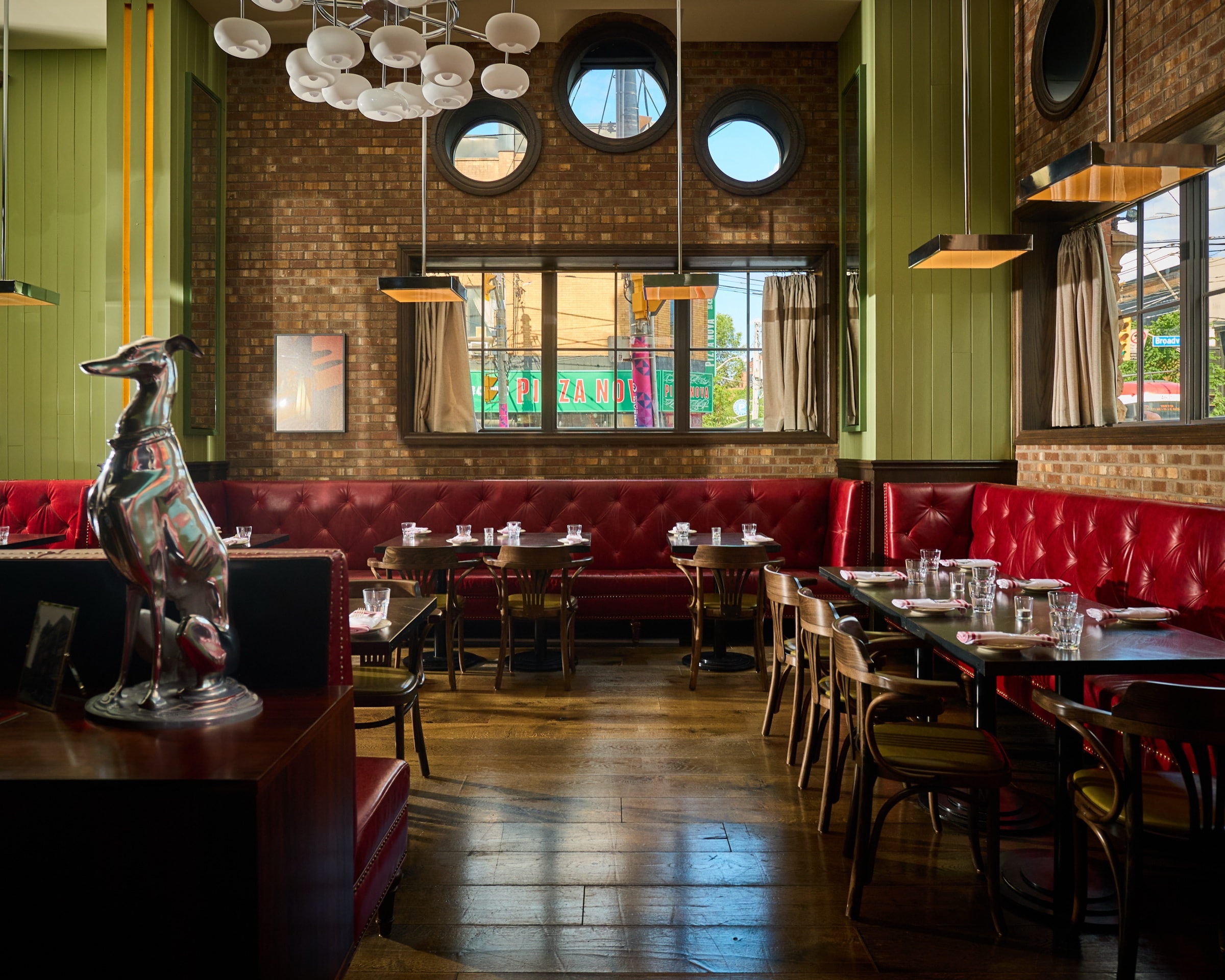 Archie's dining room set with glassware, red leather banquettes, wood chairs, chandeliers, and round windows